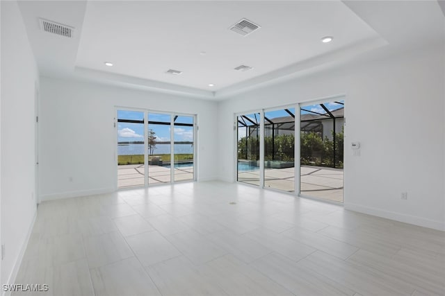 spare room featuring a tray ceiling, a sunroom, and visible vents