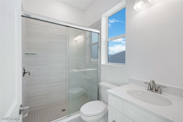 bathroom featuring a shower with door, vanity, and toilet