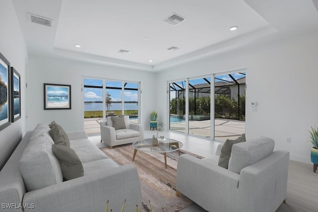 living area featuring visible vents, a tray ceiling, and a sunroom