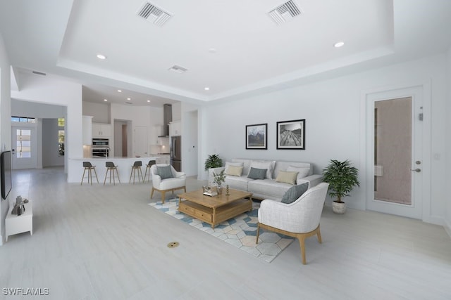 living area with visible vents, a tray ceiling, and recessed lighting