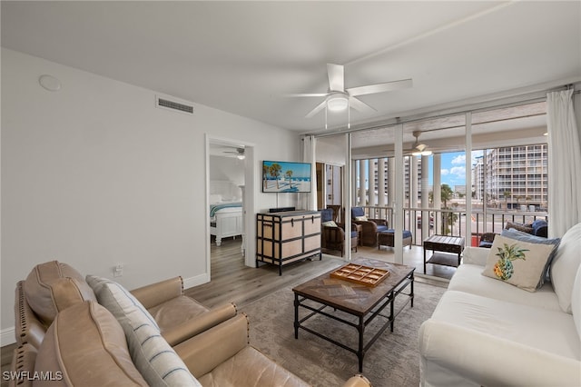 living room with hardwood / wood-style floors, ceiling fan, and a wall of windows