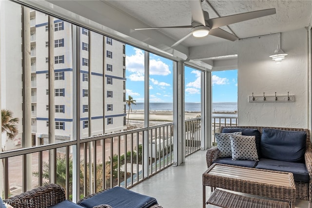 sunroom / solarium with ceiling fan, a water view, and a beach view