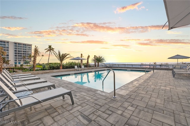 pool at dusk featuring a patio