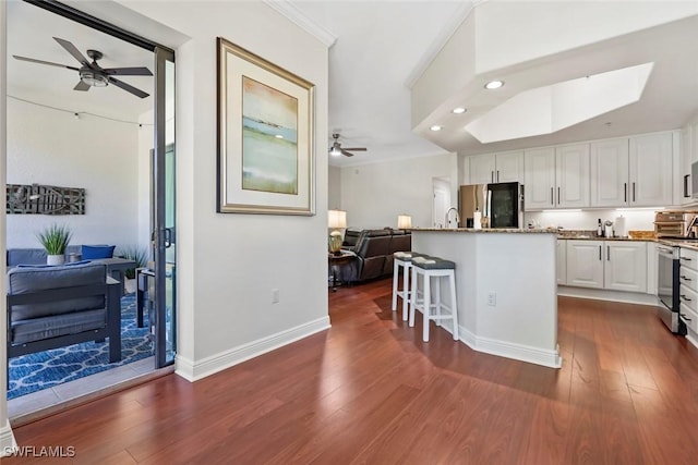 kitchen with a center island, stainless steel appliances, dark hardwood / wood-style floors, a breakfast bar, and white cabinets