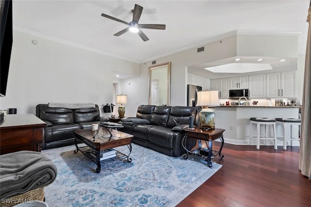 living room with dark hardwood / wood-style flooring, ceiling fan, and crown molding