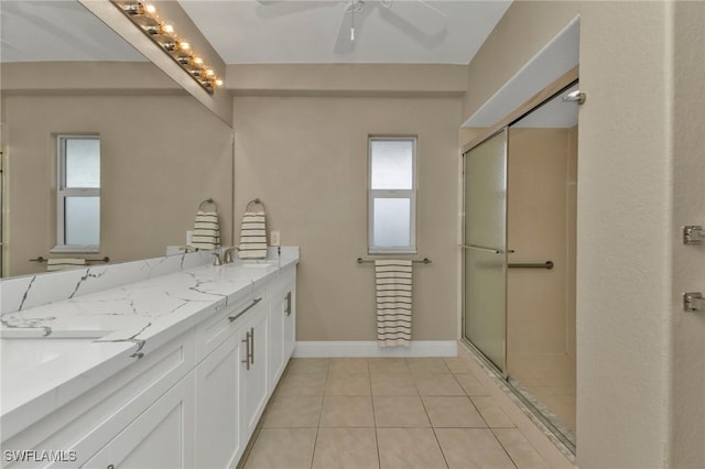 full bath with double vanity, ceiling fan, a shower stall, baseboards, and tile patterned floors