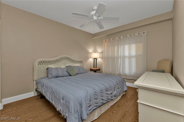 bedroom featuring wood finished floors, a ceiling fan, and baseboards