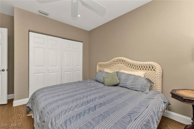 bedroom with wood finished floors, a ceiling fan, visible vents, baseboards, and a closet