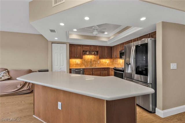 kitchen with visible vents, a raised ceiling, stainless steel appliances, light countertops, and a sink