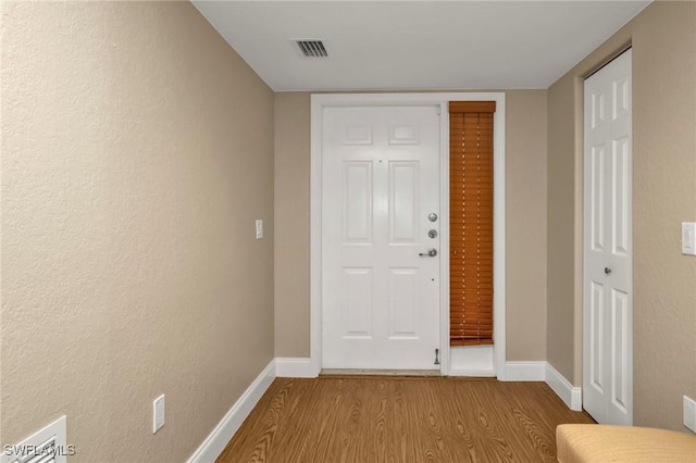 foyer featuring light wood-type flooring, visible vents, and baseboards