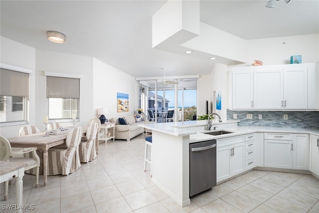 kitchen with dishwasher, kitchen peninsula, decorative backsplash, light tile patterned flooring, and white cabinetry