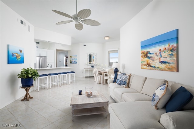 tiled living room with ceiling fan and sink