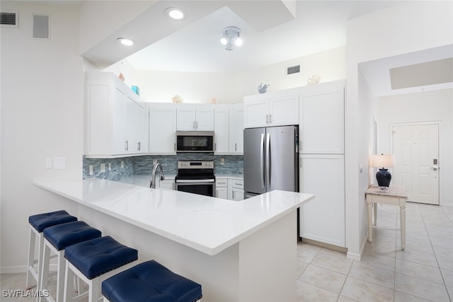 kitchen with white cabinets, a breakfast bar, kitchen peninsula, and stainless steel appliances