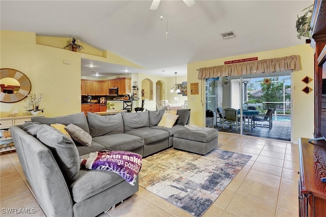 living room featuring ceiling fan with notable chandelier, light tile patterned flooring, and vaulted ceiling