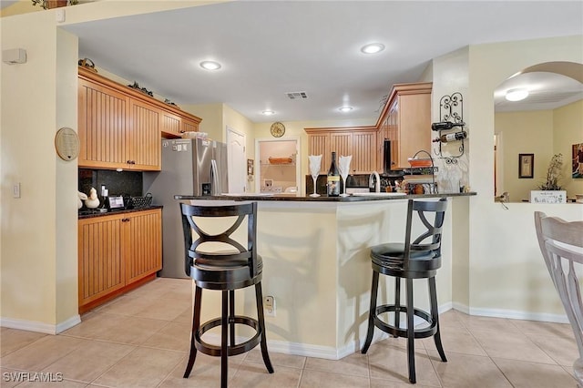 kitchen with a kitchen breakfast bar, kitchen peninsula, decorative backsplash, and light tile patterned flooring