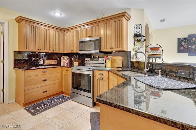 kitchen with kitchen peninsula, appliances with stainless steel finishes, light tile patterned floors, and sink