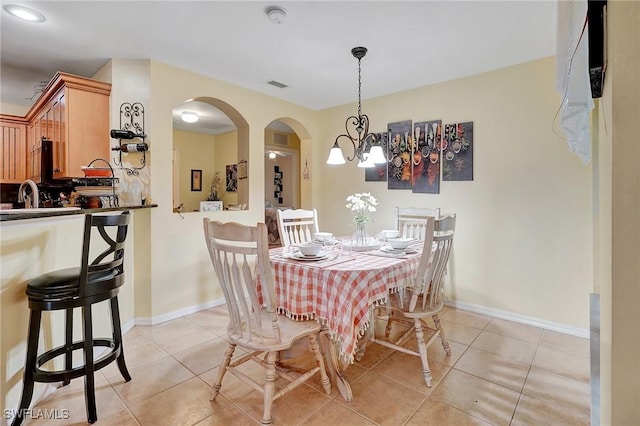 tiled dining space featuring sink and an inviting chandelier