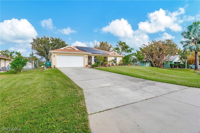 ranch-style home with solar panels, cooling unit, a garage, and a front yard