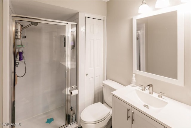 bathroom with toilet, vanity, and a shower with door