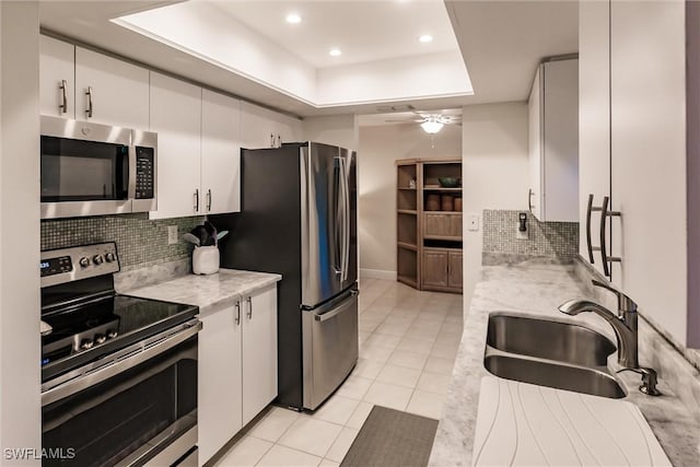 kitchen with white cabinetry, appliances with stainless steel finishes, a raised ceiling, and sink