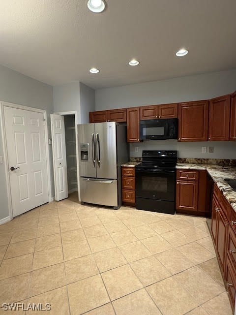 kitchen featuring light tile patterned flooring, light stone countertops, and black appliances