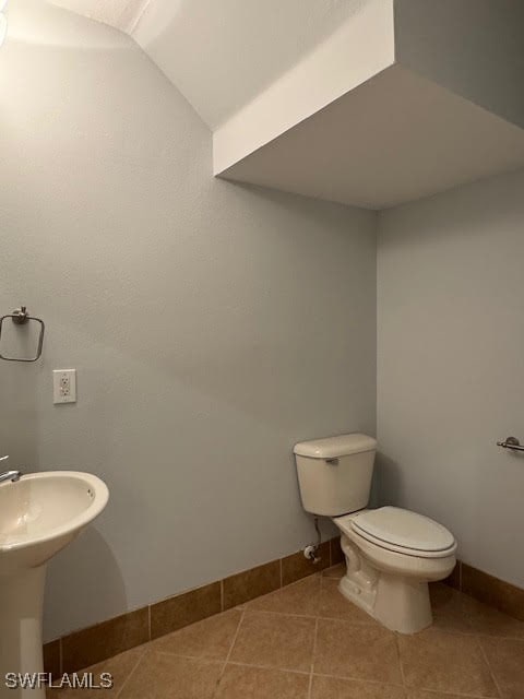 bathroom featuring toilet, lofted ceiling, sink, and tile patterned flooring