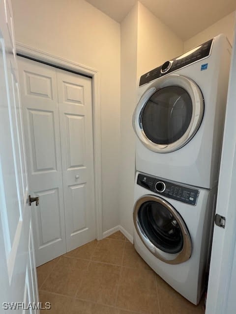 washroom with stacked washer / dryer and light tile patterned floors