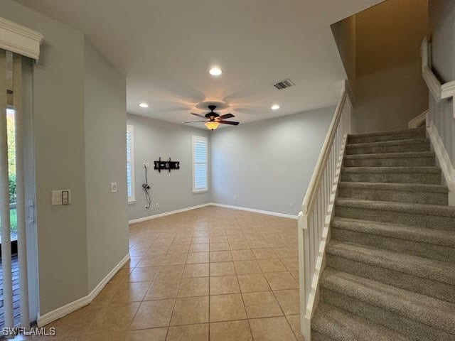 staircase with tile patterned floors, a healthy amount of sunlight, and ceiling fan