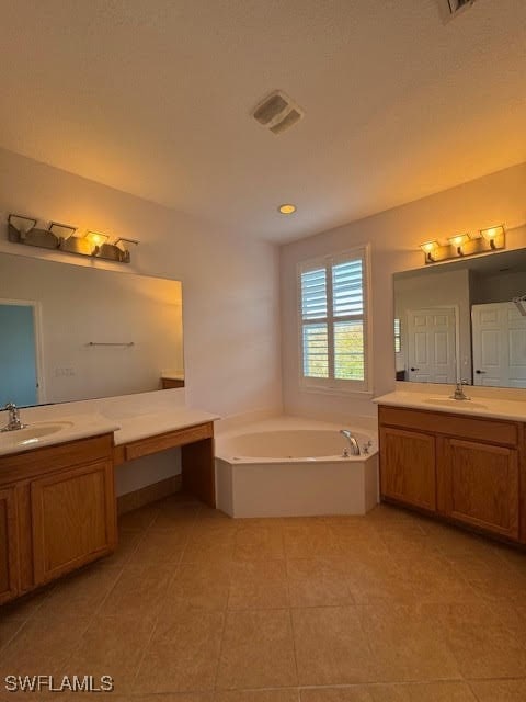 bathroom with a washtub, vanity, and tile patterned floors