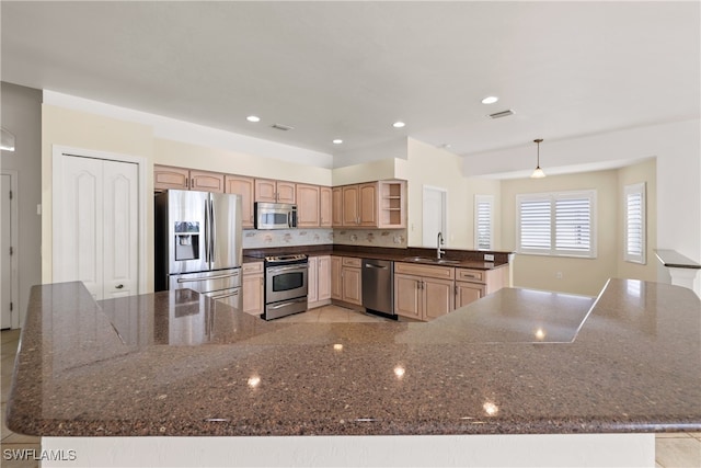 kitchen featuring decorative backsplash, appliances with stainless steel finishes, sink, light brown cabinets, and pendant lighting