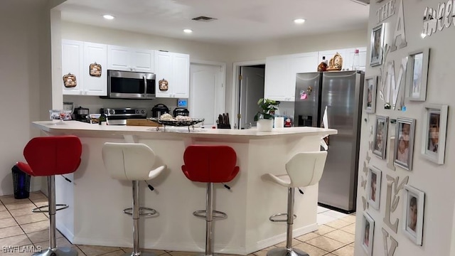 kitchen featuring kitchen peninsula, white cabinetry, a breakfast bar area, and appliances with stainless steel finishes