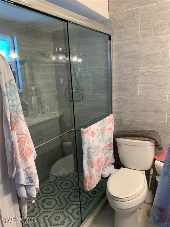 bathroom with tile walls, toilet, and walk in shower