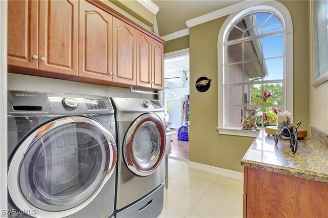 washroom featuring cabinets, washing machine and dryer, and light tile patterned floors