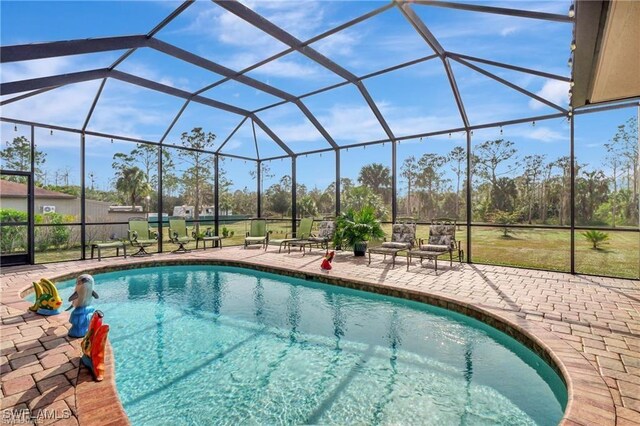 view of pool featuring glass enclosure and a patio area