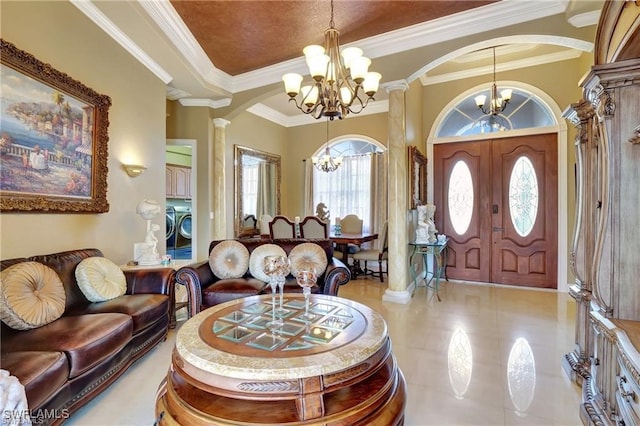 tiled foyer featuring a raised ceiling, washer and clothes dryer, an inviting chandelier, and ornate columns