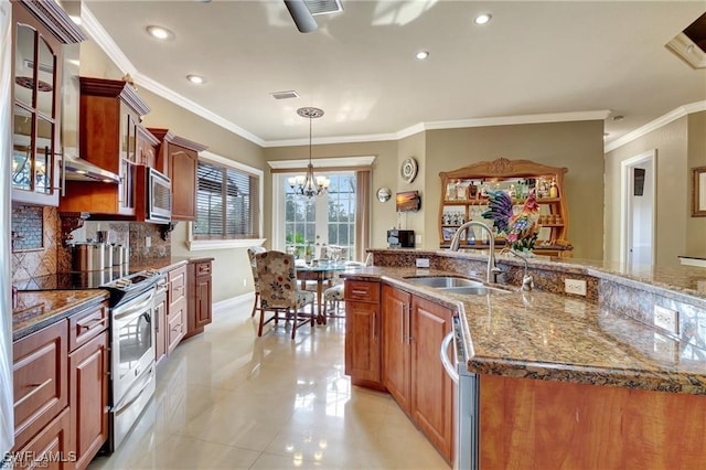 kitchen with sink, backsplash, hanging light fixtures, stainless steel appliances, and an island with sink