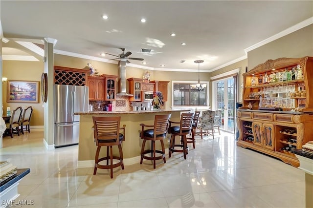 kitchen featuring pendant lighting, tasteful backsplash, a kitchen bar, stainless steel appliances, and wall chimney exhaust hood