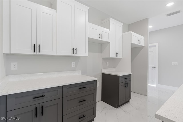 kitchen with light stone countertops and white cabinetry