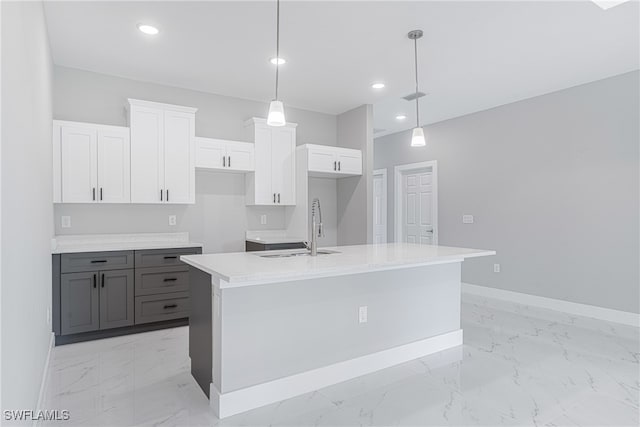 kitchen featuring sink, white cabinets, hanging light fixtures, and a kitchen island with sink