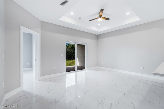 empty room featuring ceiling fan and a tray ceiling