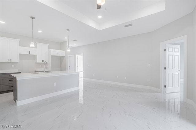 kitchen with hanging light fixtures, ceiling fan, white cabinetry, a kitchen island with sink, and sink