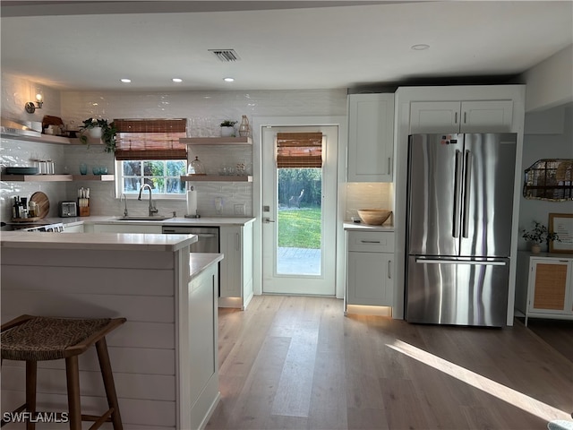 kitchen with stainless steel refrigerator, white cabinetry, and plenty of natural light