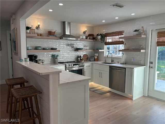 kitchen with appliances with stainless steel finishes, light stone countertops, a breakfast bar, white cabinets, and kitchen peninsula