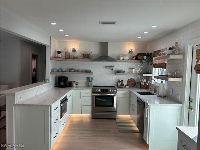 kitchen featuring backsplash, kitchen peninsula, appliances with stainless steel finishes, and extractor fan