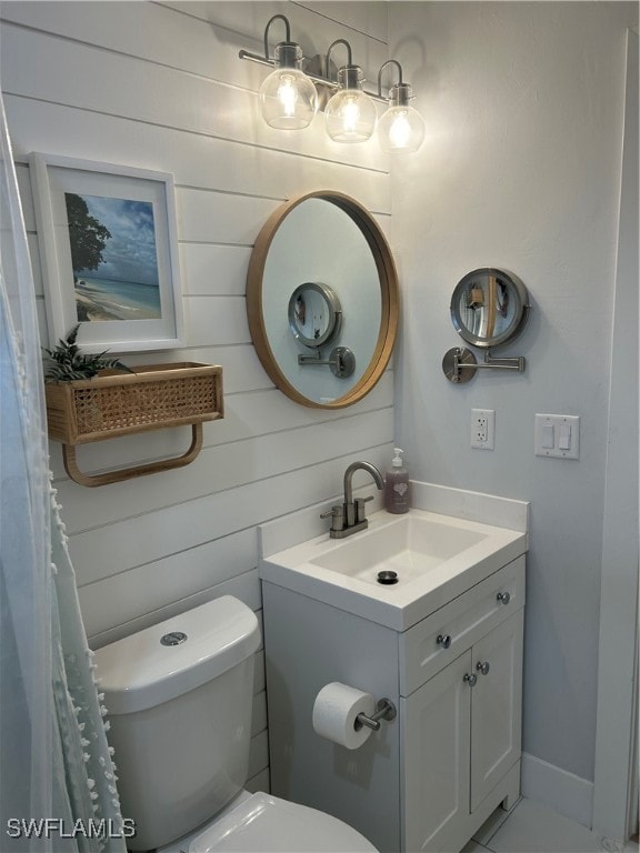 bathroom featuring wood walls, vanity, and toilet