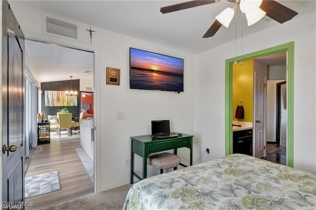 bedroom featuring ensuite bathroom, light colored carpet, and ceiling fan with notable chandelier