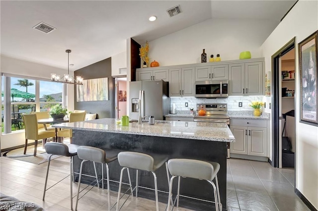 kitchen with appliances with stainless steel finishes, an island with sink, a chandelier, and gray cabinets