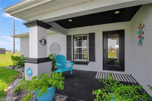 doorway to property featuring covered porch and stucco siding