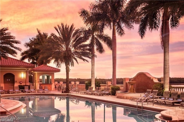 pool at dusk featuring a patio