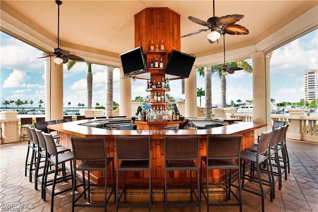 view of patio with ceiling fan and a bar